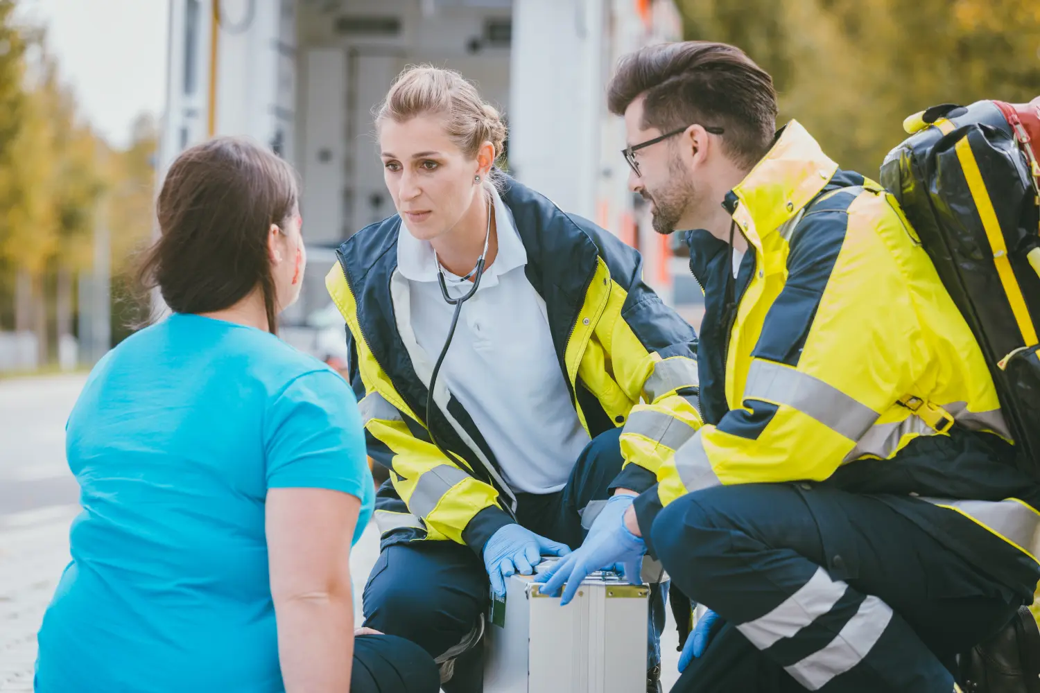 Notfallsanitäter im Gespräch mit verletzter Frau vor dem Rettungswagen