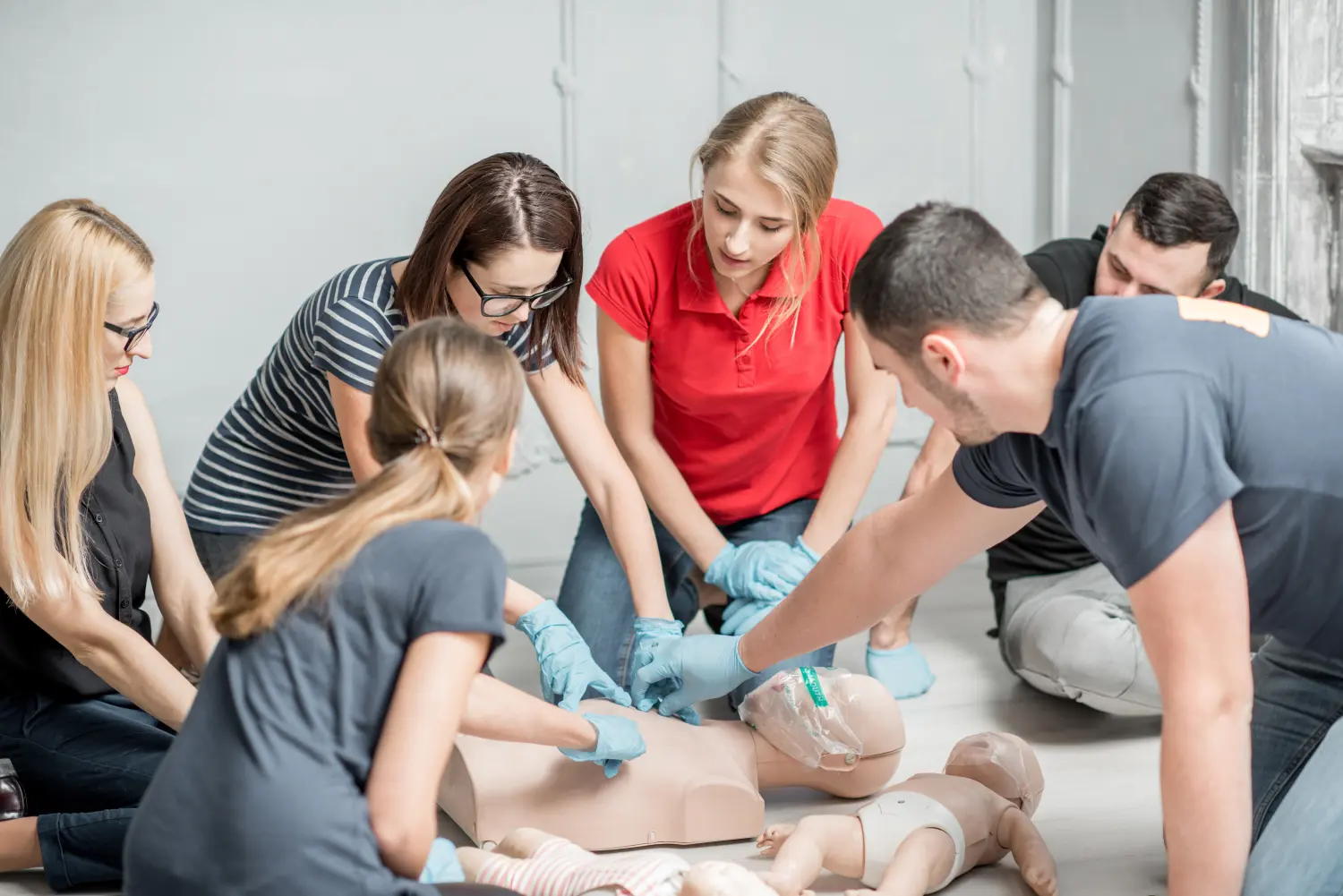 Eine Gruppe von Personen lernt die Herzdruckmassage mit Dummys während der Ausbildung in der Halle